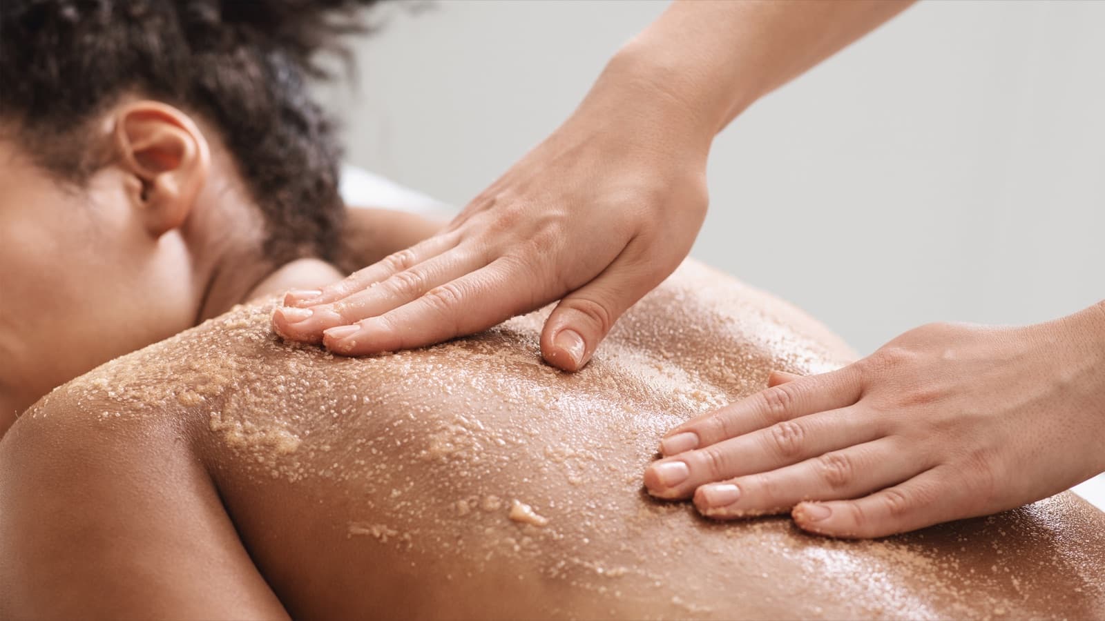 An exfoliating scrub being worked across the shoulders and back