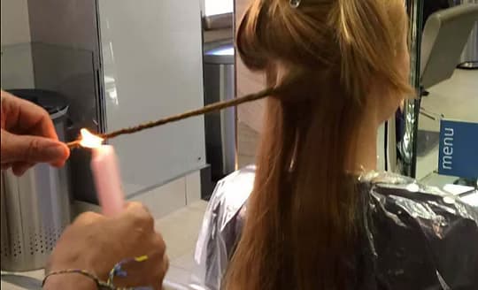Candling in progress, a candle flame run along a twisted section to singe split ends