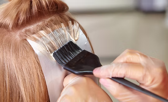Colour being painted onto a sectioned strand with a tint brush