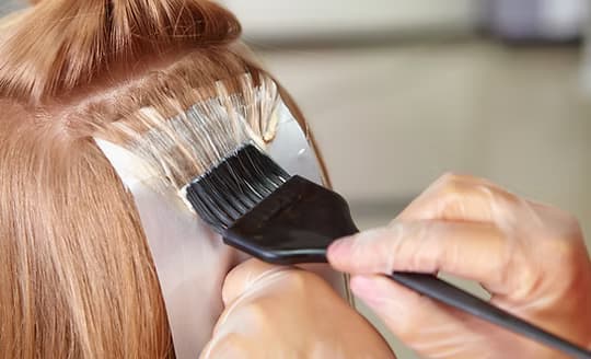 Colour being painted onto a sectioned strand with a tint brush
