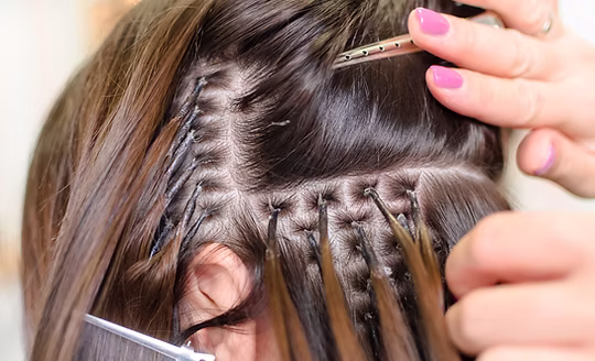 Hair extensions being fitted strand by strand at Glory