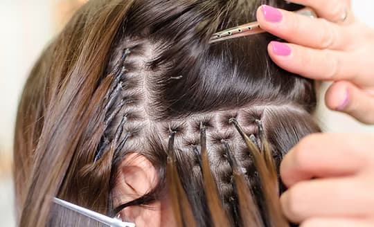 Hair extensions being fitted strand by strand at Glory