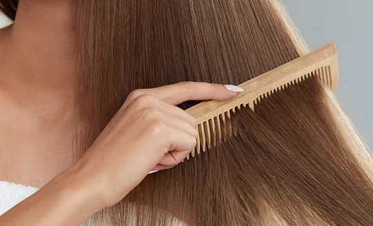 A wooden comb drawn through smooth, conditioned hair