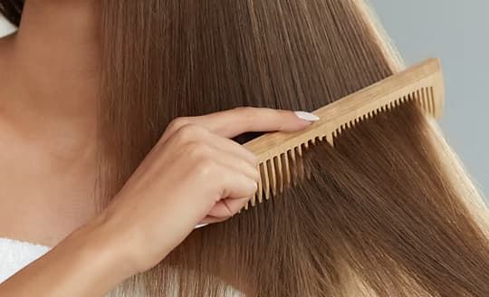 A wooden comb drawn through smooth, conditioned hair
