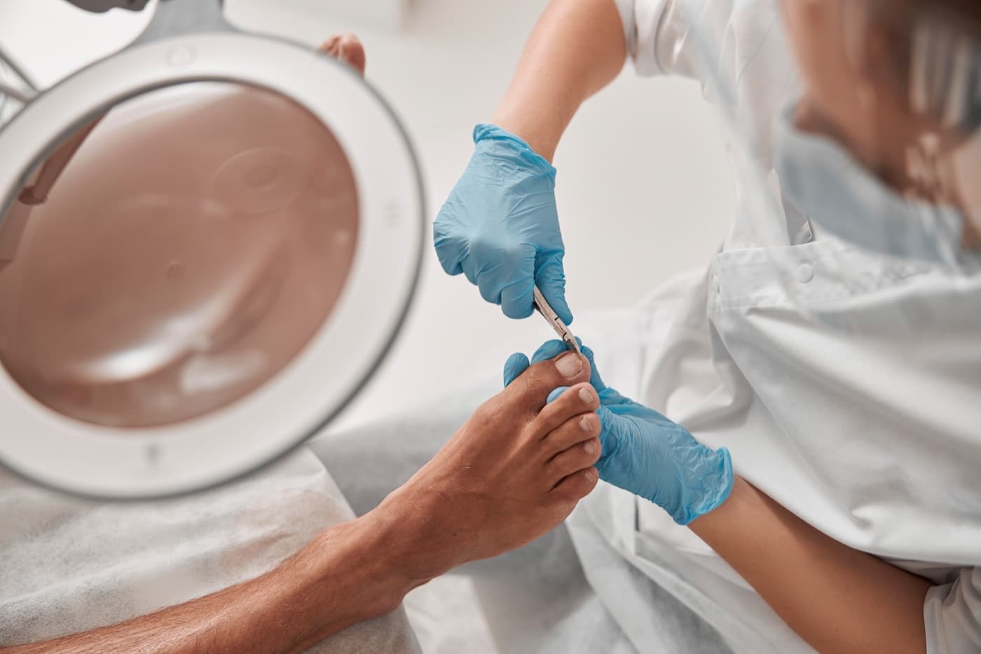 A gloved technician easing an ingrown toenail free with sterilised tools