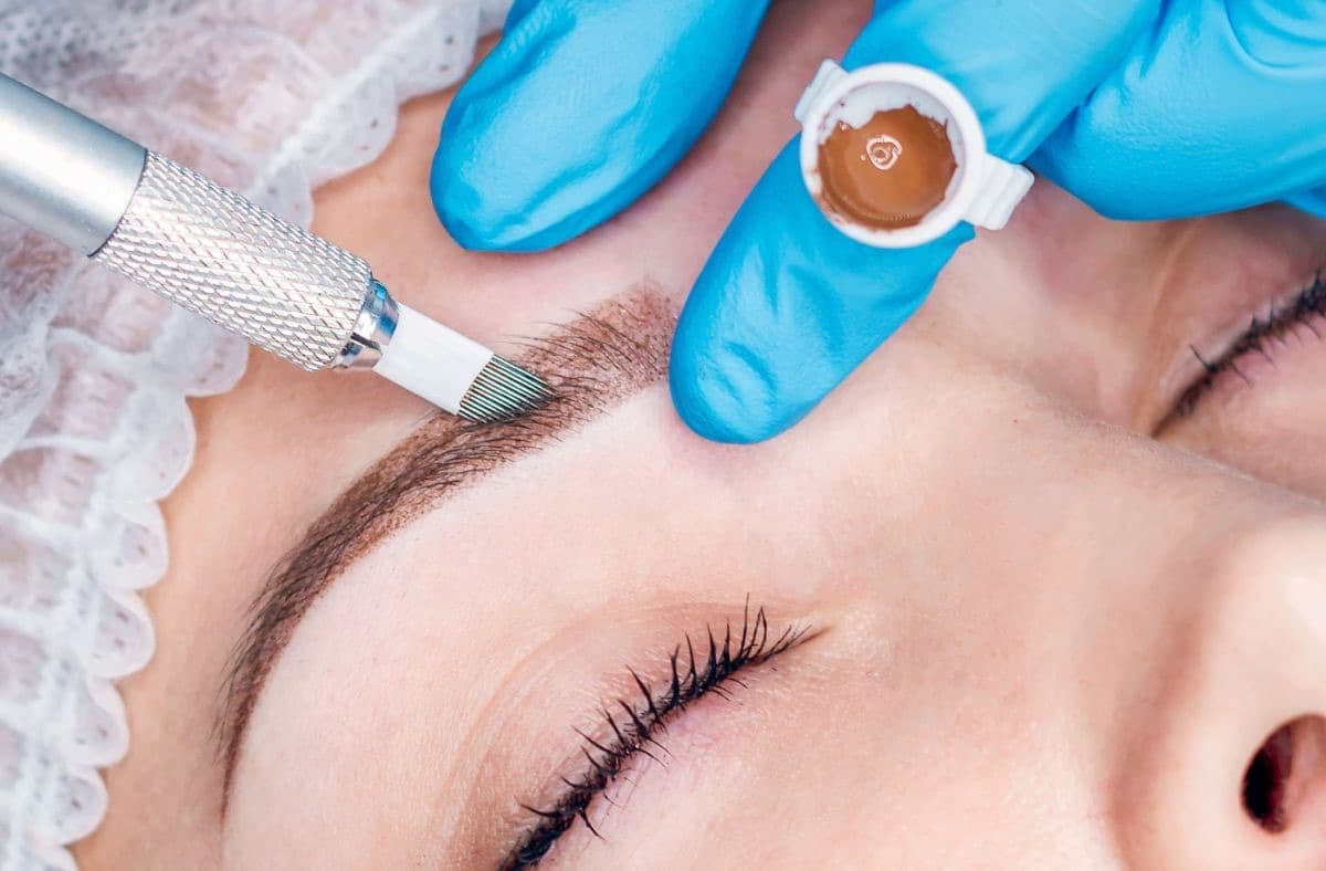 Microblading in progress, fine hair-like strokes drawn along the brow