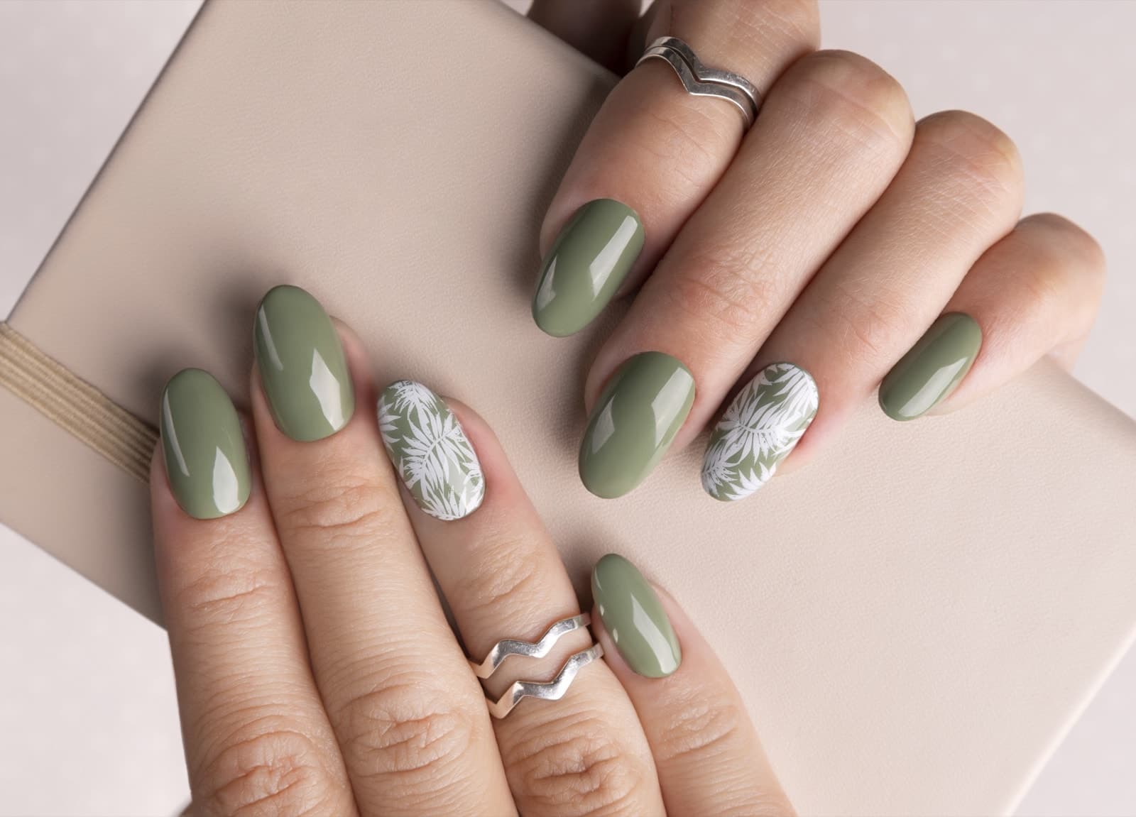 Sage green gel nails with hand-painted white leaf detail