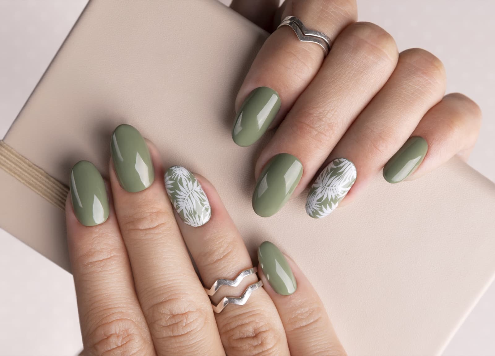 Sage green gel nails with hand-painted white leaf detail