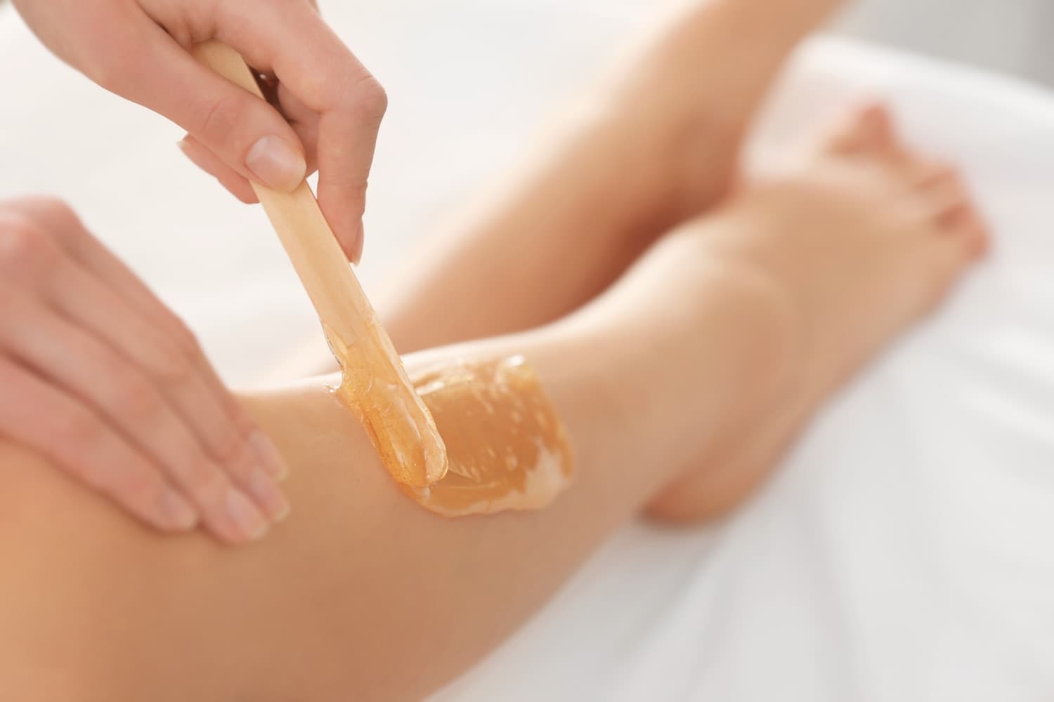 Warm wax being spread along the leg with a spatula